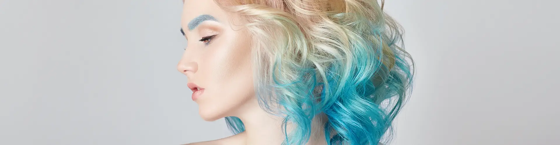 Mulher com cabelo ondulado azul e loiro, coloração ombré e styling